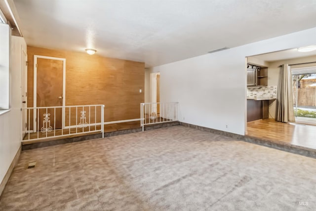 empty room featuring visible vents, carpet, and baseboards