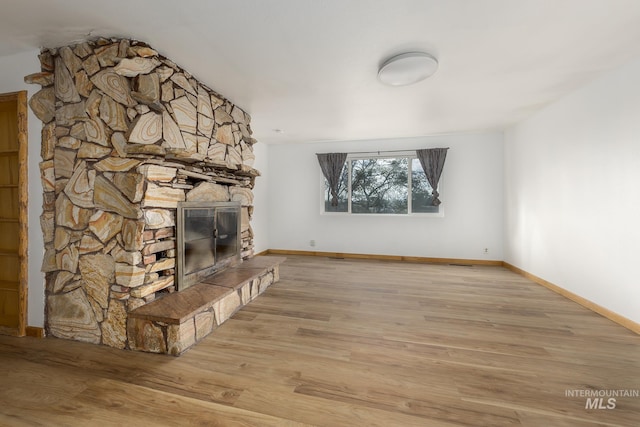 unfurnished living room featuring a stone fireplace and light hardwood / wood-style flooring