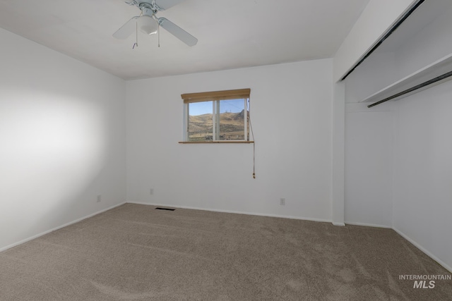 carpeted spare room with ceiling fan