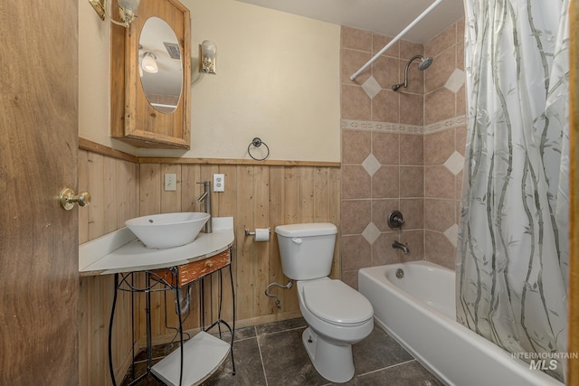 full bathroom featuring tile patterned flooring, shower / tub combo with curtain, wooden walls, toilet, and sink