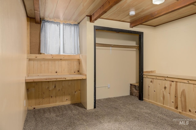 unfurnished bedroom with wood walls, wood ceiling, beam ceiling, and a closet