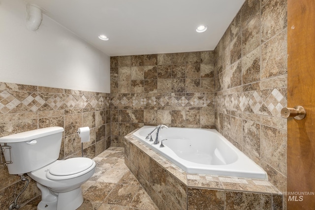 bathroom featuring a relaxing tiled tub, tile walls, and toilet