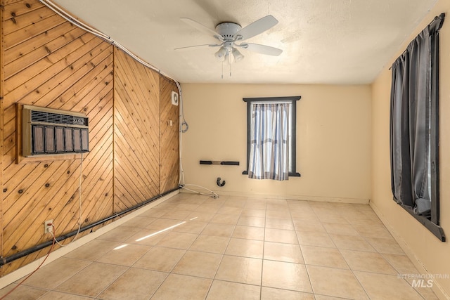 tiled spare room with ceiling fan, a textured ceiling, and wood walls