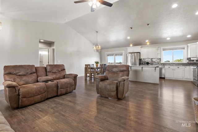 living room with plenty of natural light, vaulted ceiling, and dark wood finished floors