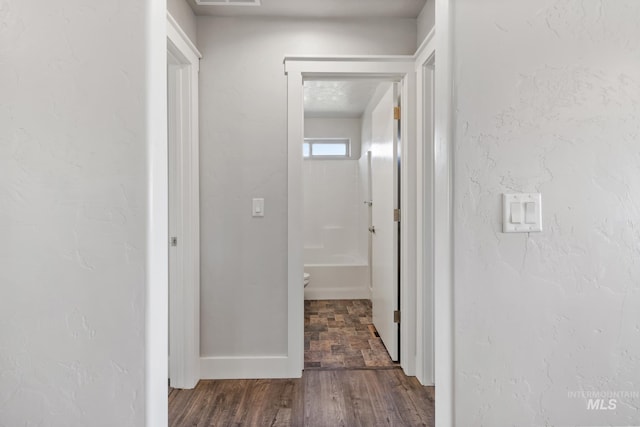 hall featuring dark wood-type flooring, visible vents, and baseboards
