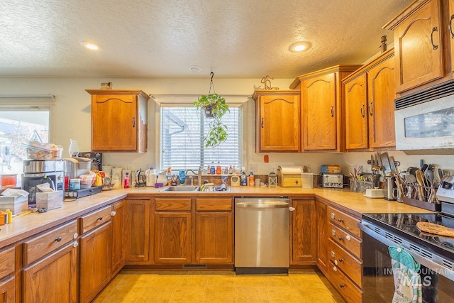 kitchen with sink, a wealth of natural light, stainless steel appliances, and a textured ceiling