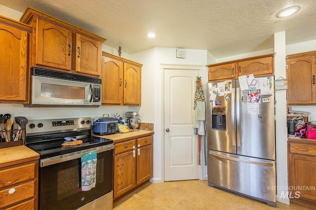 kitchen with a textured ceiling and appliances with stainless steel finishes