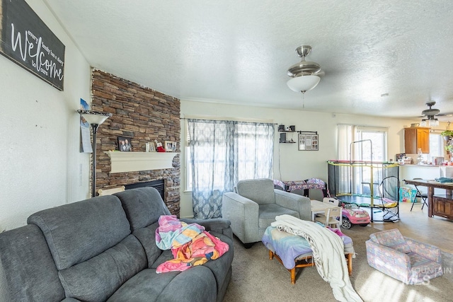 living room with ceiling fan, a textured ceiling, and a fireplace