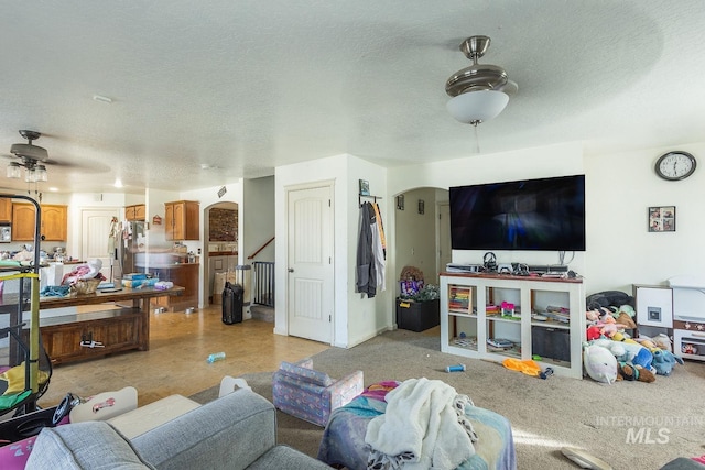 living room with ceiling fan and a textured ceiling