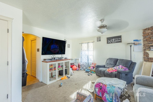 carpeted living room with ceiling fan and a textured ceiling