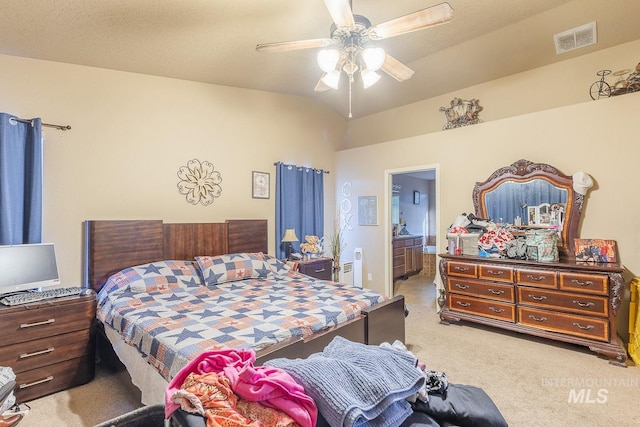 carpeted bedroom with ceiling fan, connected bathroom, and a textured ceiling
