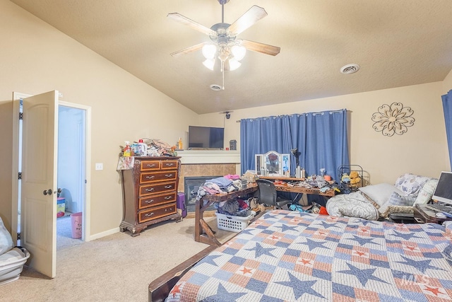 carpeted bedroom with ceiling fan, a tile fireplace, and lofted ceiling