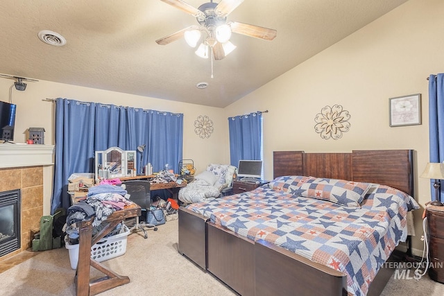 bedroom featuring ceiling fan, light colored carpet, a tile fireplace, and lofted ceiling