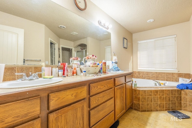 bathroom featuring tiled bath, a textured ceiling, tile patterned floors, and vanity