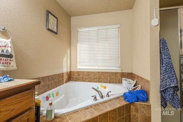 bathroom with a textured ceiling, shower with separate bathtub, and vanity