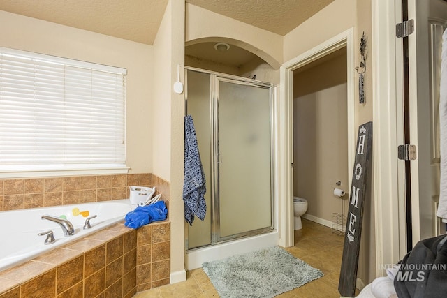bathroom with a textured ceiling, toilet, and plus walk in shower
