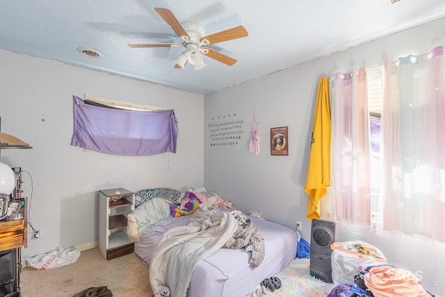 carpeted bedroom with ceiling fan and a textured ceiling
