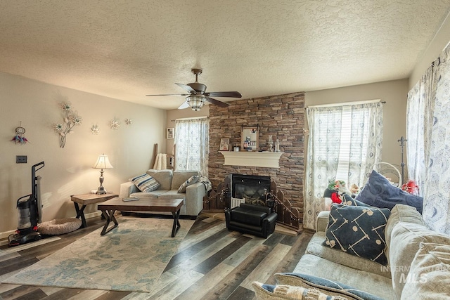living room featuring a textured ceiling, a healthy amount of sunlight, and a stone fireplace