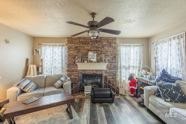 living room featuring ceiling fan, a wealth of natural light, hardwood / wood-style flooring, and a fireplace