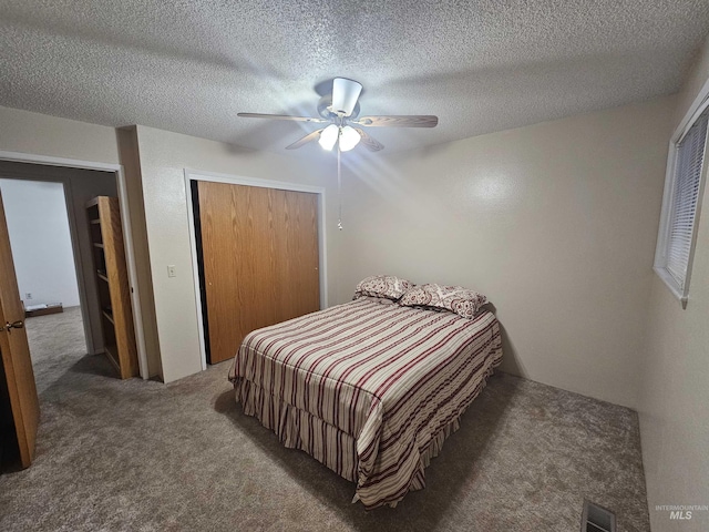 carpeted bedroom featuring a ceiling fan, a closet, visible vents, and a textured ceiling