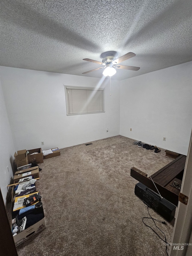 interior space with ceiling fan, carpet floors, and a textured ceiling