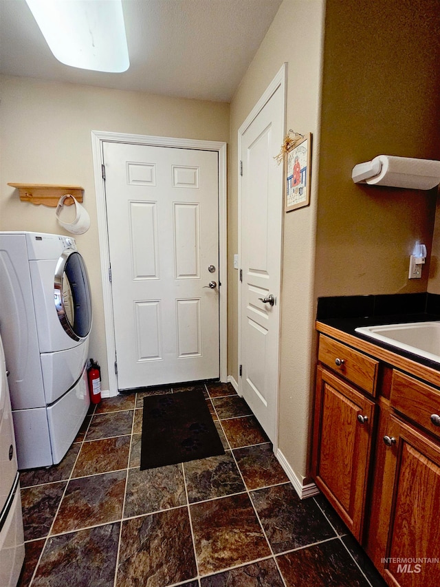 clothes washing area with sink, washer / clothes dryer, and dark tile floors