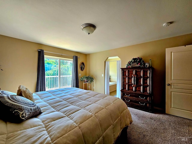 bedroom with ensuite bathroom, carpet, and access to exterior