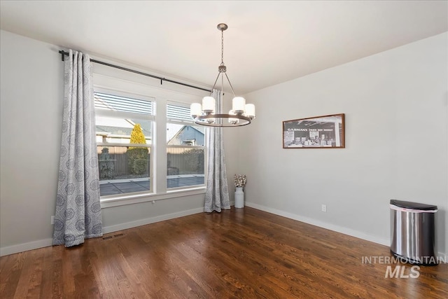 unfurnished dining area with an inviting chandelier and dark hardwood / wood-style flooring