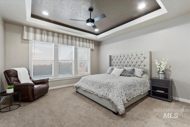 carpeted bedroom featuring ceiling fan, a textured ceiling, and a tray ceiling