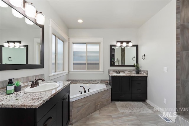 bathroom featuring tiled tub and vanity