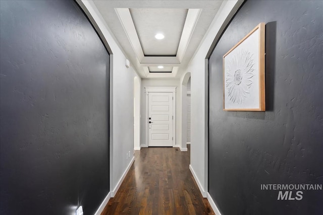 corridor with dark hardwood / wood-style flooring and a raised ceiling