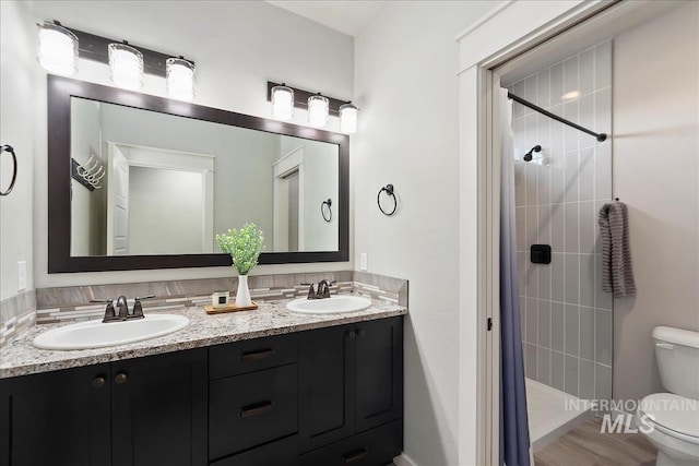 bathroom featuring a tile shower, vanity, and toilet