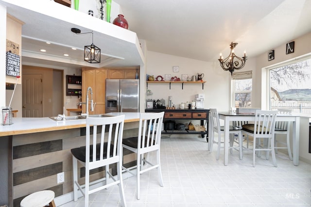 kitchen with open shelves, stainless steel fridge with ice dispenser, a chandelier, pendant lighting, and a sink