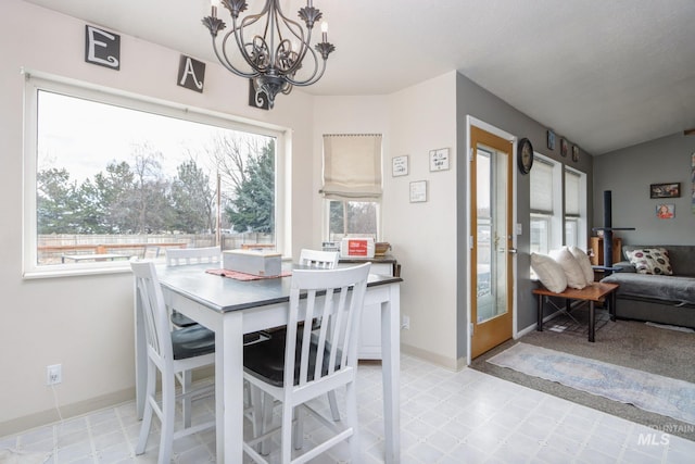 dining room with an inviting chandelier, light floors, and baseboards