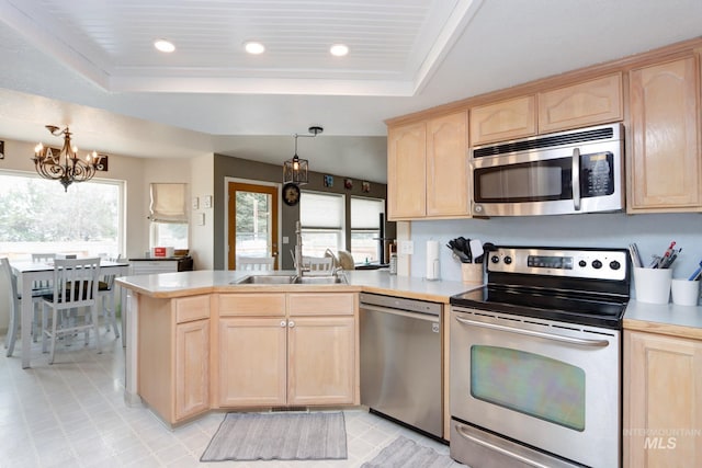 kitchen featuring a raised ceiling, a peninsula, stainless steel appliances, and light brown cabinetry