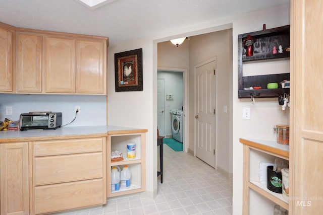 kitchen featuring light countertops, a toaster, independent washer and dryer, and light brown cabinetry