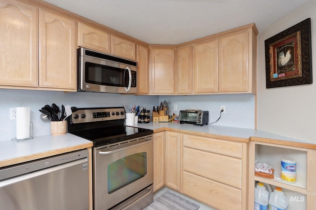 kitchen with light countertops, a toaster, light brown cabinetry, and stainless steel appliances