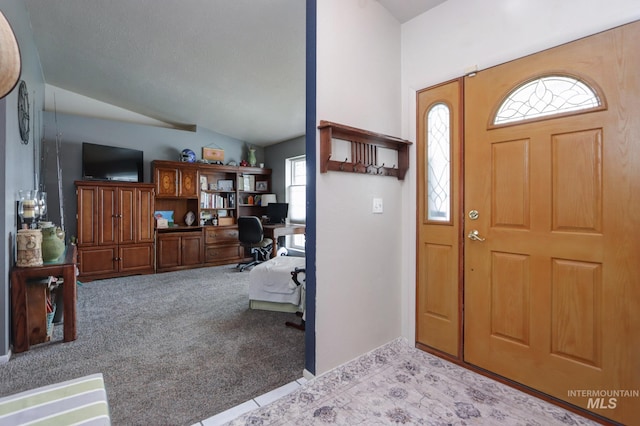 carpeted foyer featuring vaulted ceiling