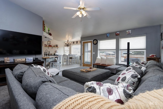 living area with a wealth of natural light and ceiling fan with notable chandelier