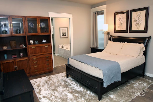 bedroom with ensuite bath, wood finished floors, and baseboards