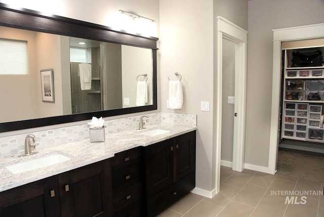 bathroom featuring tile patterned floors, double vanity, a shower stall, and a sink