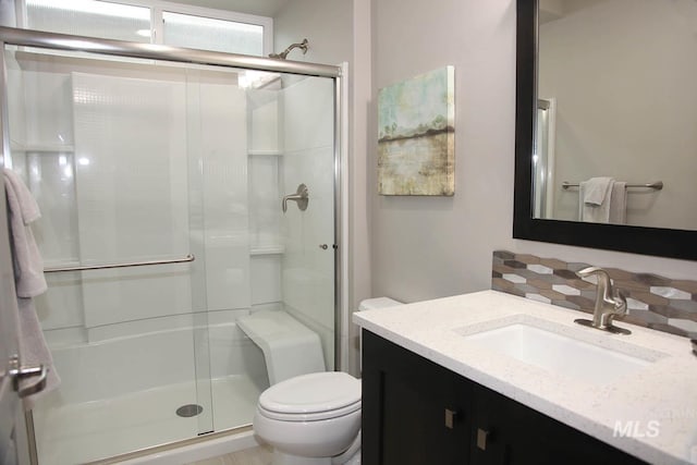 bathroom with backsplash, a stall shower, toilet, and vanity