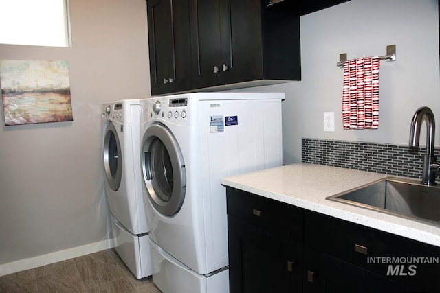 laundry area featuring separate washer and dryer, cabinet space, baseboards, and a sink