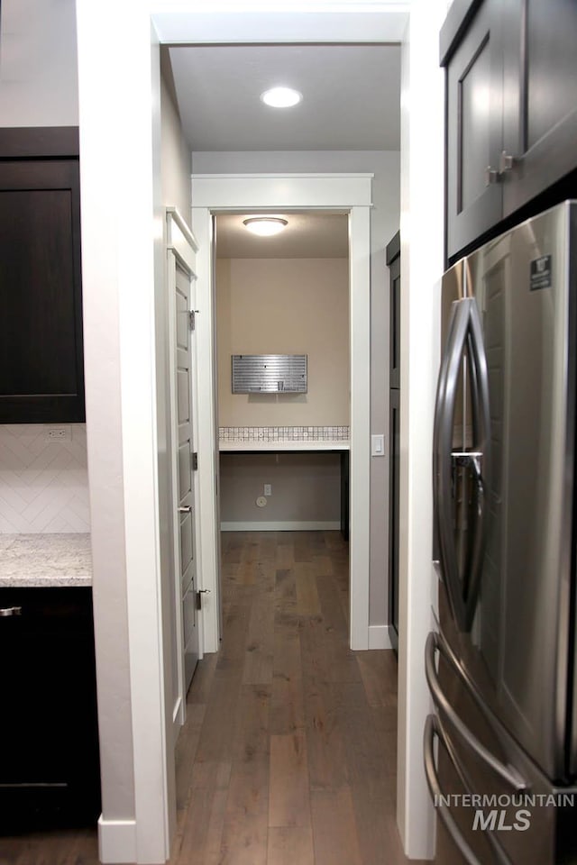 kitchen featuring light stone counters, backsplash, wood finished floors, freestanding refrigerator, and baseboards