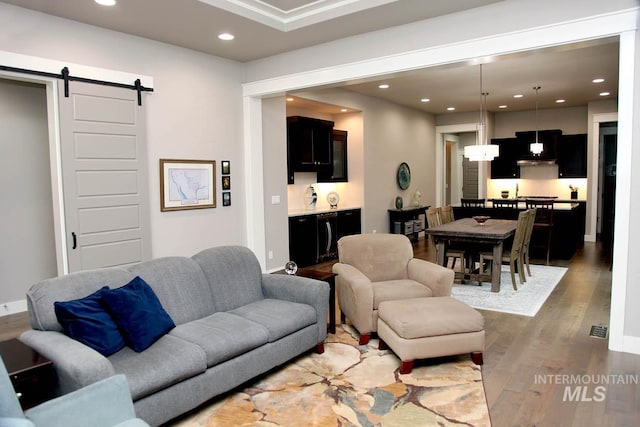 living room featuring recessed lighting, baseboards, a barn door, and wood finished floors