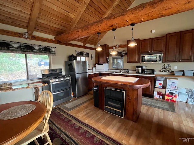 kitchen with vaulted ceiling with beams, stainless steel appliances, a kitchen island, dark hardwood / wood-style floors, and hanging light fixtures