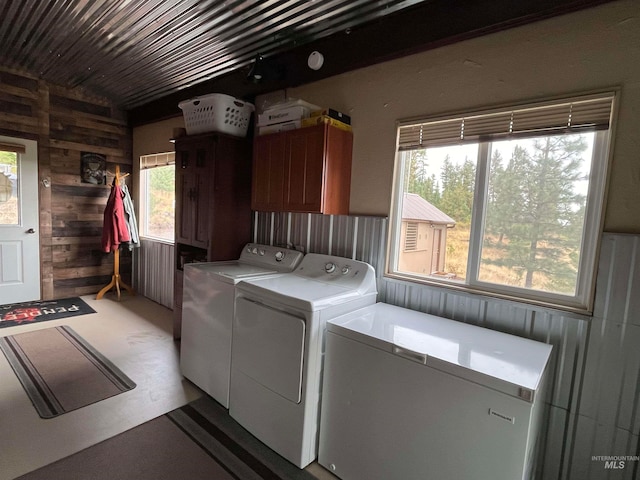 washroom featuring wood walls, cabinets, and washing machine and clothes dryer