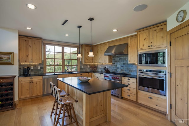 109 Angani Way Unit 15, Sun Valley, ID 83353 - kitchen featuring appliances with stainless steel finishes, wall chimney exhaust hood, dark countertops, light wood finished floors, and beverage cooler