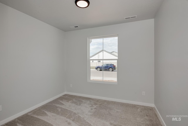 carpeted spare room with baseboards and visible vents