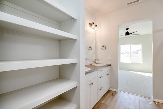 bathroom with wood finished floors, visible vents, double vanity, ceiling fan, and a sink